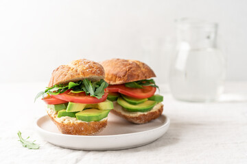 Avocado sandwich with hummus and tomatoes on white background side view with copy space. Healthy snack, fast food