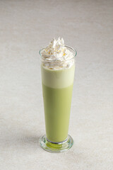 Portion of green matcha latte with whipped cream