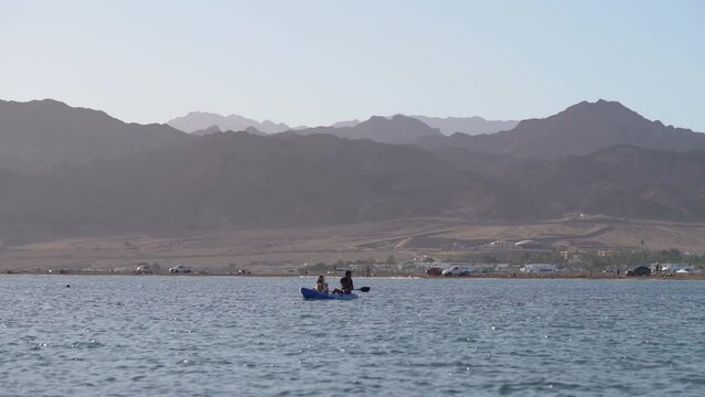 People Kayaking In The Red Sea On A Sunny Day With Desert Mountains in the Background - wide