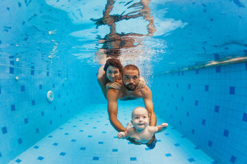 Happy family - mother, father with baby boy swimming, diving underwater with fun in blue pool. Healthy lifestyle, active parents, people water sports activity on summer vacation with child