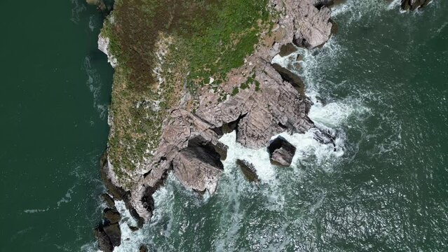 Torquay, Torbay, South Devon, England: DRONE AERIAL VIEWS: The drone flies from south-to-north over Thatcher Rock giving a direct, overhead view of the island, waves and the sea.