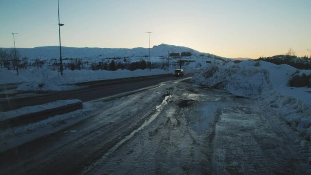 Car with headlights on, driving at dusk on a deserted snow-covered road in severe frost. Swedish-Norwegian border crossing near the town of Storlien
