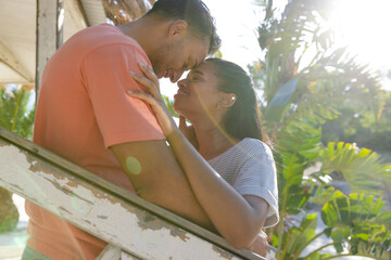 Caucasian romantic young couple with eyes closed and face to face standing by wooden railing