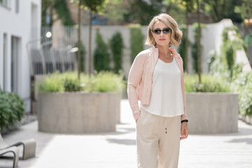 Obraz premium Portrait of Beautiful White Caucasian Adult Woman She is Wearing Active Lifestyle Outdoor Sportwear. Dark Sunglass. Vilnius, Lithuania. White t-shirt.