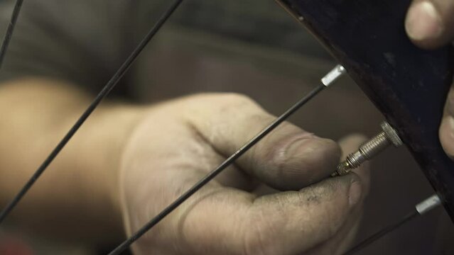 A bicycle mechanic adjusting the air valve of a bicycle inner tube.