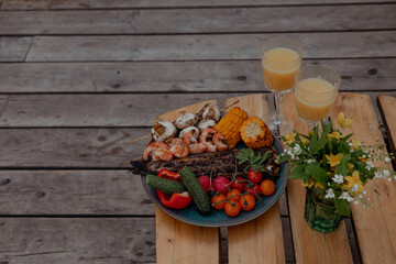 Grilled fish and shrimp with vegetables on the picnic table