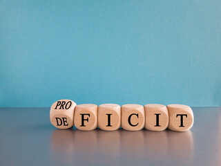 Proficit or deficit symbol. Turned wooden cube and changes the concept word deficit to proficit. Beautiful light blue background. Business proficit or deficit concept. Copy space. - obrazy, fototapety, plakaty