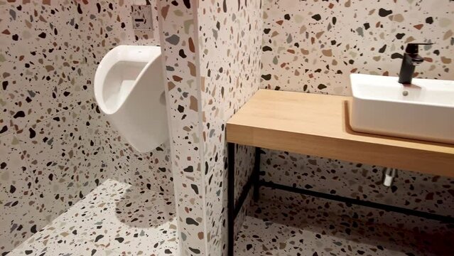 Modern clean public toilet with ceramic urinal, with hygienic automatic water-saving electronic flusher. Urine sensor urinal Inductive toilet flush. Office or public bathroom. 