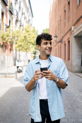 Young man with curly hair using smartphone