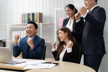 Cheerful business people excited their achievement with smile. Asian businessman and team looking at computer screen together happy celebrating success sales growth. Entrepreneur successful startup.