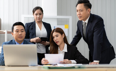 Business mentor meeting with team in office looking at computer screen training management concept. Asian businessman work together with executive colleague group talking mentoring leadership idea.