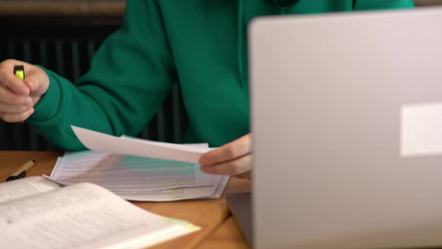 paper documents working female businessman holding papers hands looking through docs, opened laptop on table. studying, learning, reports, charts and records. concept working day education homework