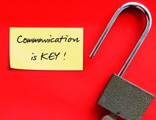 Lock pad, stick note on red background with handwritten text COMMUNICATION IS KEY, means...