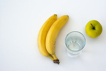 Banana, apple and glass of water isolated on white background