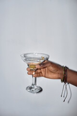 Minimal closeup of young man holding martini glass during party, shot with flash
