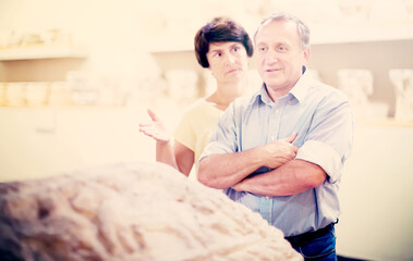 mature couple turists examines basrelief of tomb in historical museum