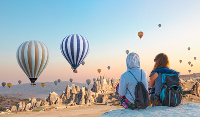 Hot air balloon flying over spectacular Cappadocia - Girls watching hot air balloon at the hill of Cappadocia 