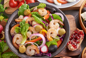 Healthy salad plate. Fresh seafood recipe. Grilled shrimps and fresh vegetable salad. Healthy food. Flat lay. Top view. Shrimp salad with tomato, olives and almond nuts. Mix vegetables.