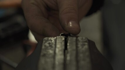 A bicycle mechanic repairing a metal plate on a workbench.