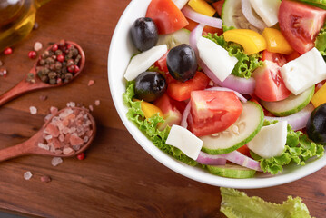 Classic greek salad of fresh vegetables, cucumber, tomato, sweet pepper, lettuce, red onion, feta cheese and olives with olive oil. Healthy food, top view