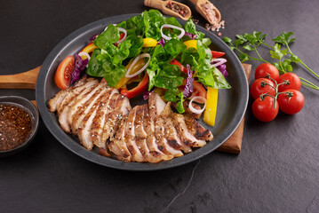 Grilled steak with fresh vegetable, sweet pepper, tomatoes, red onion, pink pepper and spices. Home made tasty food. Concept for tasty and healthy meal. Black stone background. Pork steak with salad