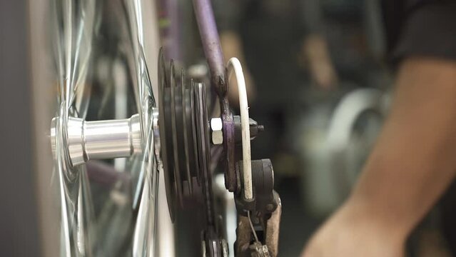 A bicycle mechanic adjusting the rear derailleur while manually rotating the pedals with their hand.