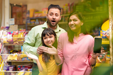 Happy family showing empty smartphone Screen at grocery shop.