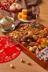 Chinese style festive atmosphere, wooden dining table, various snacks, pastries, lanterns, gifts, red envelopes, fish, Chinese food, dumplings(Translation:The text means auspicious and good luck)