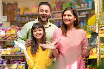 Happy family showing empty smartphone Screen at grocery shop.