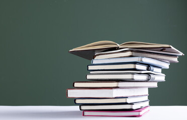 Close up of stack of books and notebooks with copy space on green background