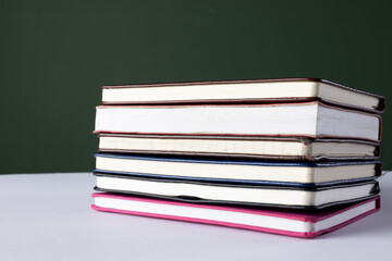 Close up of stack of books and notebooks with copy space on green background