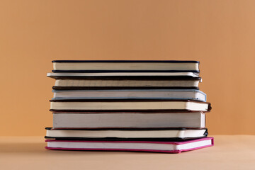 Close up of stack of books and notebooks with copy space on orange background