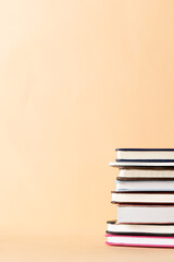 Close up of stack of books and notebooks with copy space on orange background