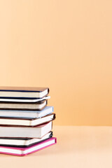 Close up of stack of books and notebooks with copy space on orange background