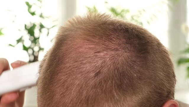 A man cuts his hair with a clipper. Haircut at home. Saving money. Barber shop at home. Change yourself. Lifestyle.