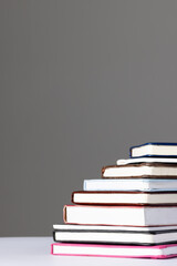 Close up of stack of books and notebooks with copy space on grey background