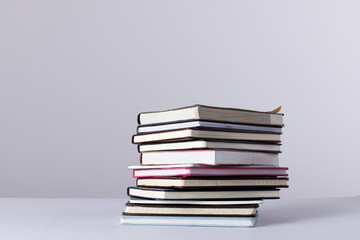 Close up of stack of books and notebooks with copy space on white background