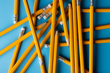 Close up of stack of yellow pencils with erasers on blue background