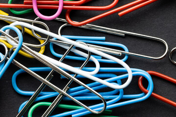 Close up of close up of multi coloured paper clips on black background