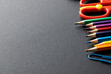 Close up of multi coloured pencils and scissors and copy space on grey background