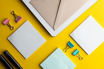 Flat lay of black pens, envelope and white paper with copy space on yellow background