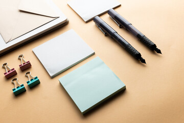 Flat lay of black pens, envelope, paper clips and memo notes with copy space on yellow background