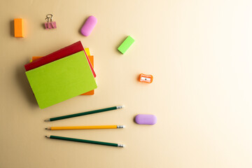 Flat lay of pencils, memo notes, sharpener and erasers with copy space on yellow background