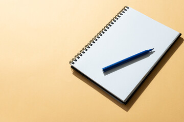 Flat lay of notebook and blue marker with copy space on yellow background