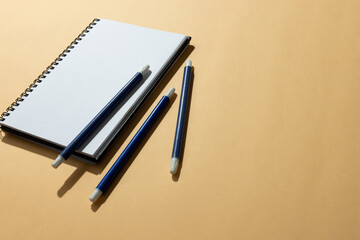 Close up of notebook and three markers with copy space on orange background
