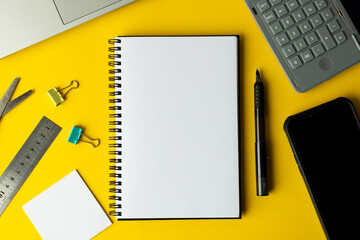 Flat lay of notebook with copy space and school materials on yellow background