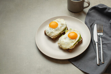 Toasts with egg and avocado on a gray background in a plate. healthy breakfast