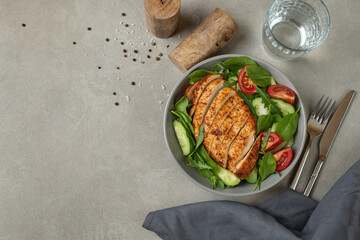 Salad with vegetables and chicken on a gray background