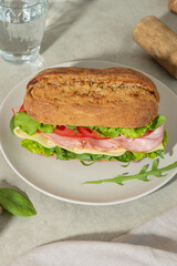 Sandwich with mortadella, cheese and tomatoes on a gray table