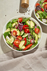 Vegetable salad with tomatoes, avocado and cucumber on a gray background
